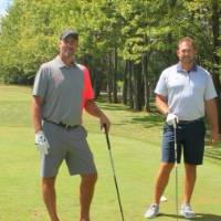 four alumni with golf clubs in the green